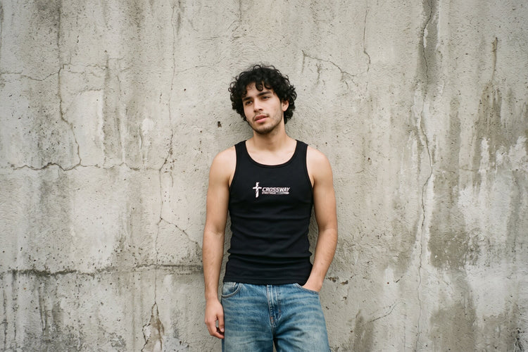 Young man leaning on a concrete wall in the black Crossway Romans 14:8 tank