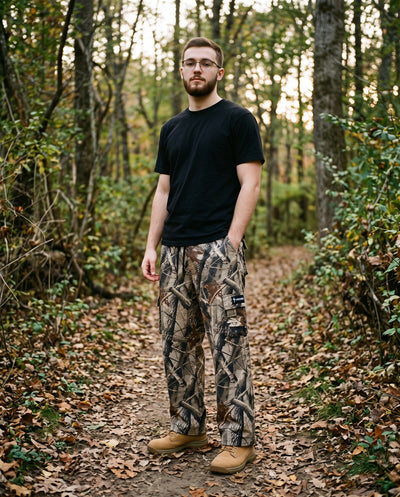 Young man in Crossway Kingdom Camo cargo sweatpants on a wooded trail